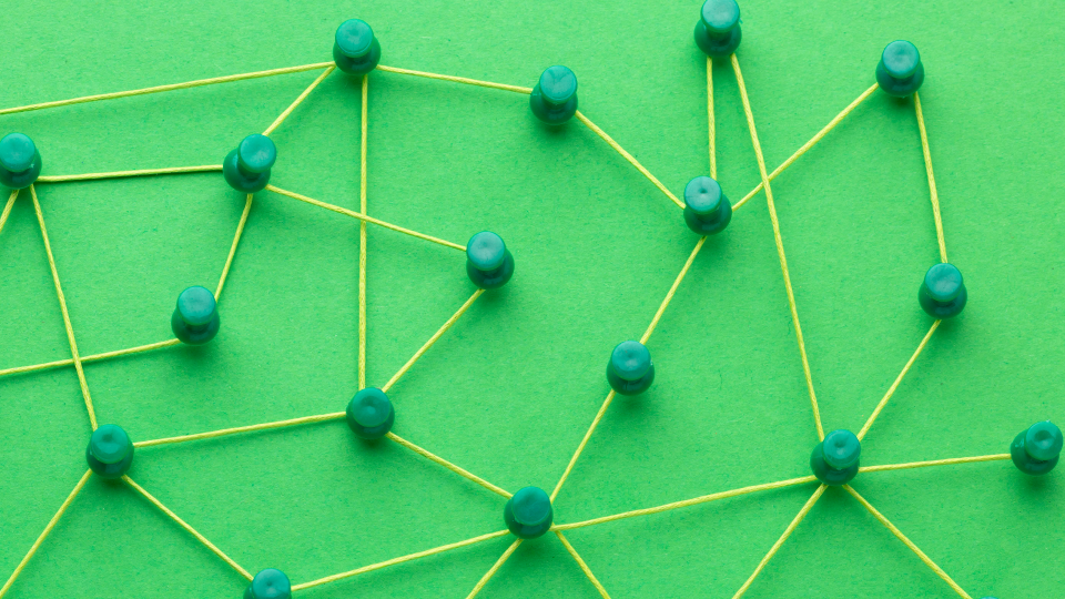 Contra um fundo verdejante, uma rede de fios amarelos se entrelaça entre contas verdes, formando um padrão geométrico. Esta representação abstrata simboliza O que são Organizações Exponenciais, ilustrando sistemas interconectados e crescimento exponencial por meio de seu design semelhante a uma teia. - Efacont