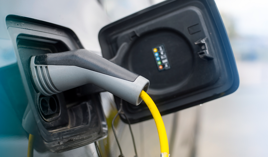 Uma imagem em close de um cabo amarelo de carregamento de veículo elétrico conectado à porta de carregamento de um carro destaca o design meticuloso dos carros elétricos. A tampa da porta está aberta, revelando detalhes, enquanto o fundo desfocado mantém seu foco neste processo dedutível de IVA. - Efacont