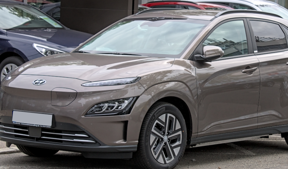 Um SUV Hyundai bege está estacionado na rua, incorporando o design elegante e futurista típico dos Carros Elétricos 2025. Seus faróis modernos e grade fechada destacam sua natureza elétrica, complementados por trilhos de teto prateados e acabamento preto. Outros veículos são visíveis ao fundo. - Efacont