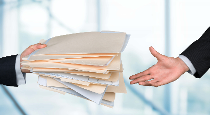 Uma pessoa de terno entrega uma grande pilha de pastas de arquivo e papéis a outra pessoa de terno, simbolizando o crescimento e as tendências 2025 na constituição de empresas em Portugal. O fundo desfocado sugere um ambiente de escritório. - Efacont