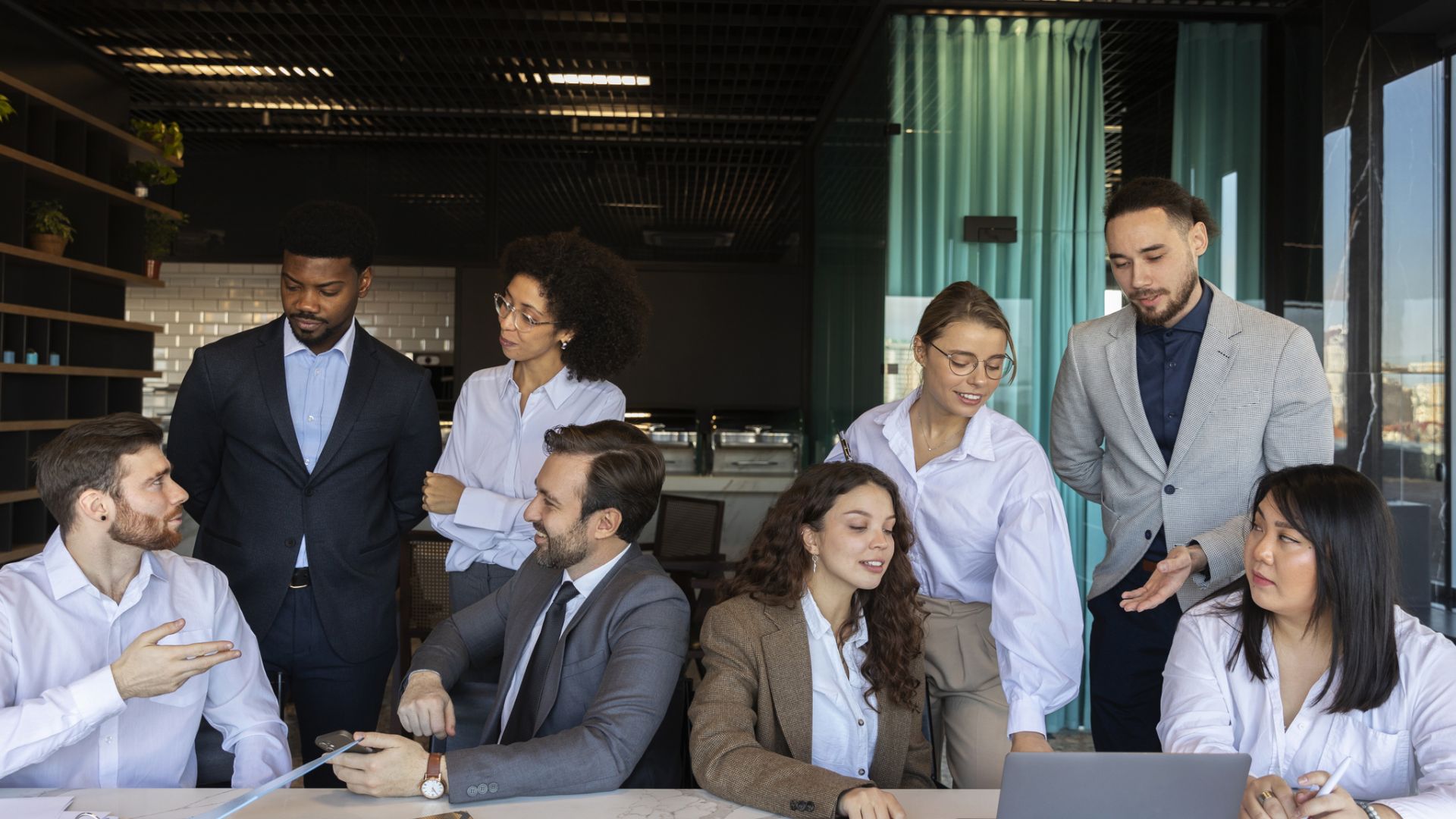 Oito pessoas vestidas profissionalmente colaboram em um escritório moderno. Quatro estão sentadas em uma mesa com laptops e papéis, enquanto quatro estão de pé atrás delas, engajadas em animadas "inet´ Internacionalização Operações em Conjunto" em meio a uma atmosfera cooperativa e uma parede de vidro como pano de fundo. - Efacont